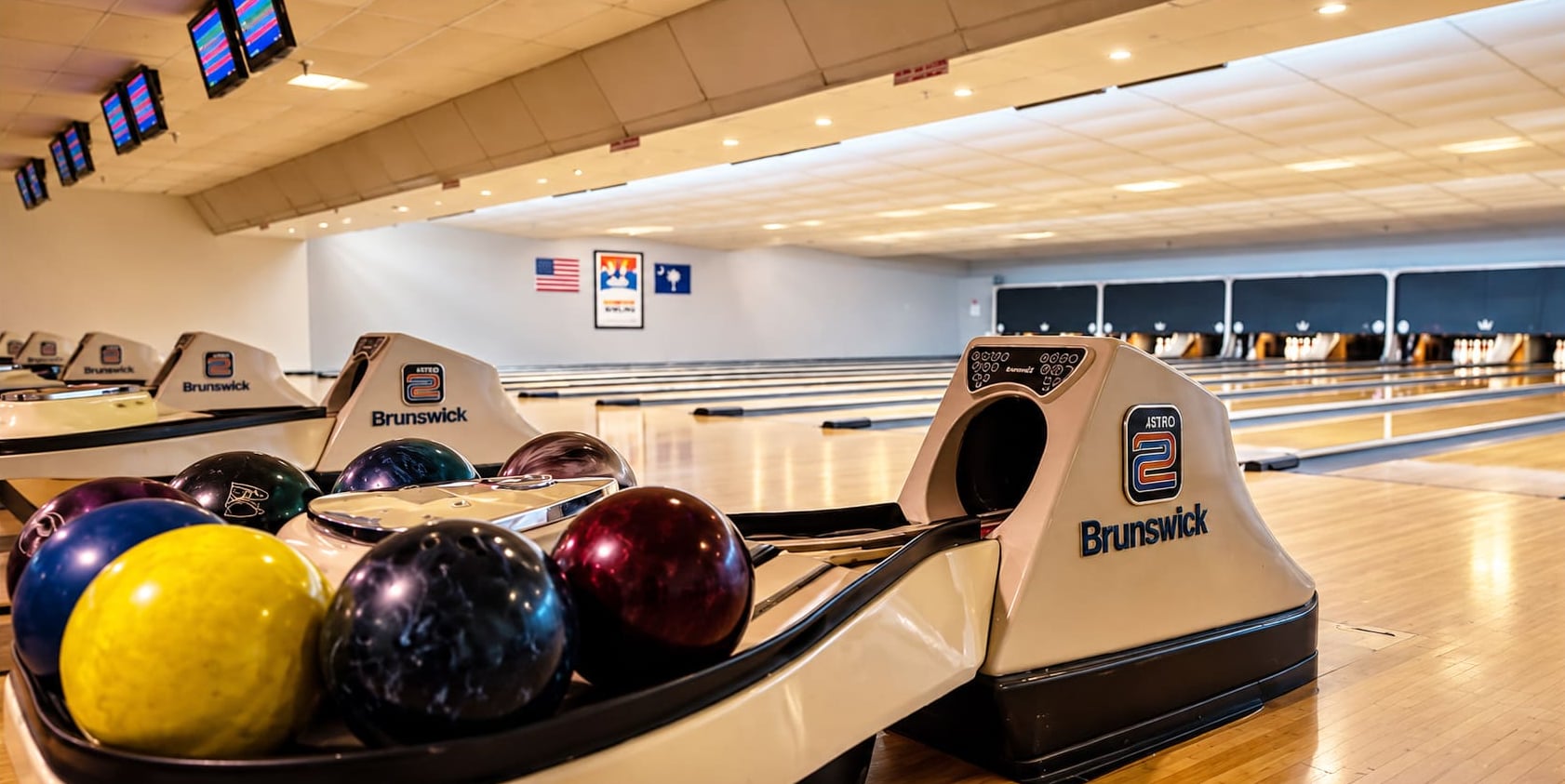 Bowling balls on a ball return with the lanes stretching into the distance