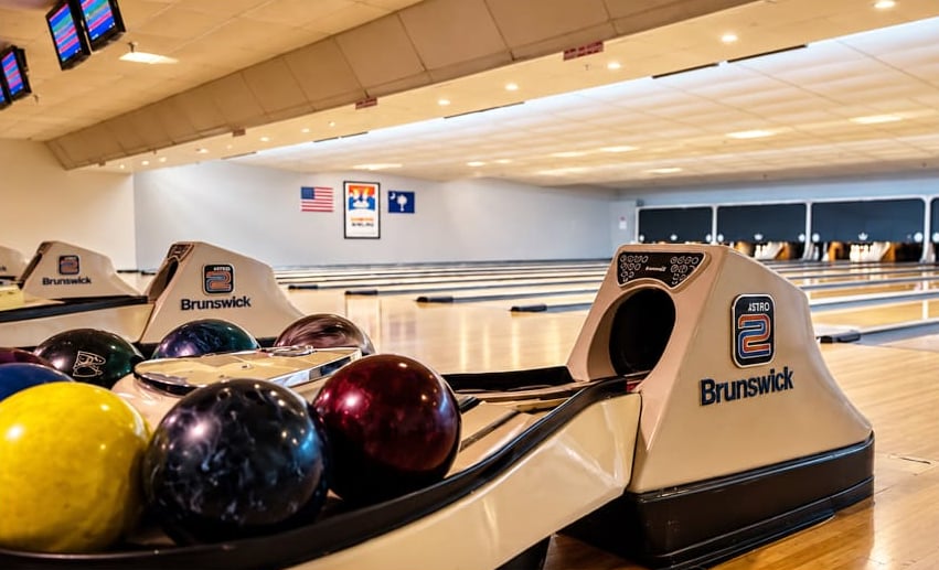 Bowling balls on a ball return with the lanes stretching into the distance