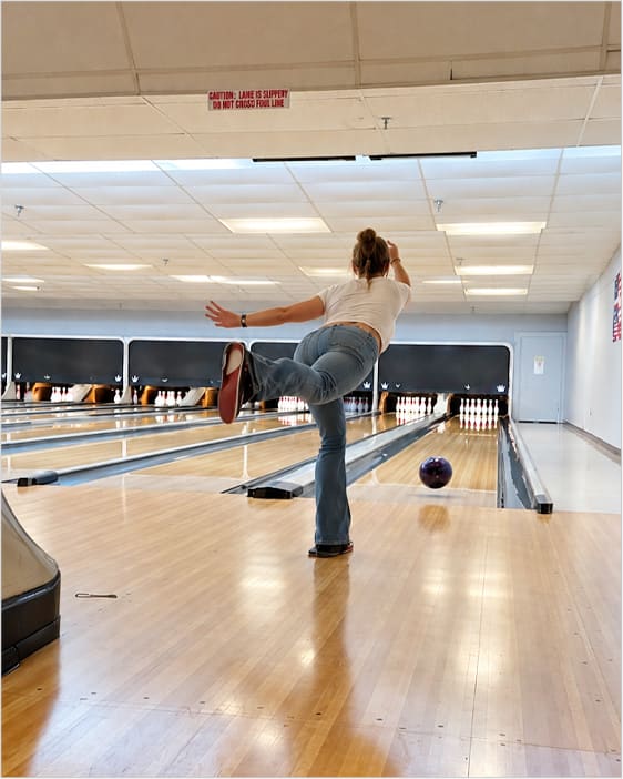 A bowler follows through on the approach as the ball rolls down the lane