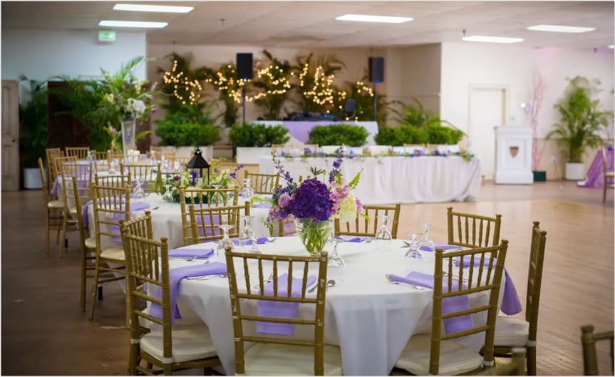 Round reception tables with centerpieces and string lights in the hall
